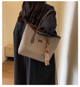 Detail of checkered tote bag featuring a leather logo patch and cute rabbit charm