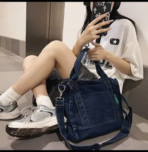Detail of dark blue washed denim tote bag with adjustable strap and front pocket