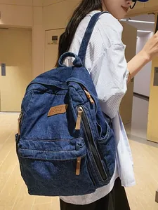 Large capacity dark blue denim backpack for women featuring multiple pockets and leather tabs