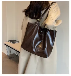 Detail of dark brown tote bag showing glossy leather texture and gold metal accents