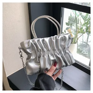 Detail of silver pleated cloud bag with luxury rhinestone handles and metal chain