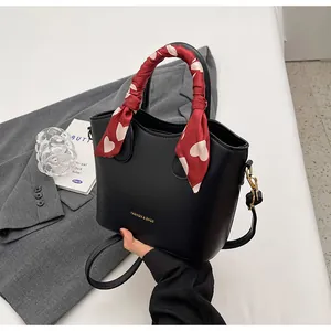 Détail du sac à main en cuir noir avec poignée en foulard de soie et boucles dorées