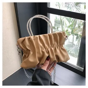 Close-up of beige pleated cloud bag with sparkling rhinestone handles and silver chain