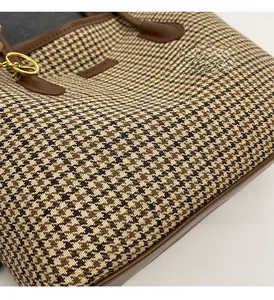 Detail of brown houndstooth tote bag featuring premium leather trim and gold metal rings