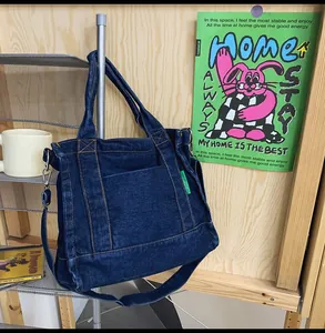 Detail of blue denim tote bag with metal hardware and green tag on a lifestyle background