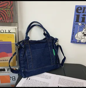 Detailed view of durable blue denim tote bag with green label and adjustable strap