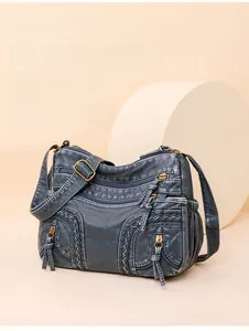 Detail of navy blue washed leather shoulder bag with woven lines and bronze hardware