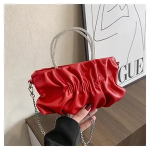 Detail of red ruched cloud bag featuring rhinestone handle and silver metal chain