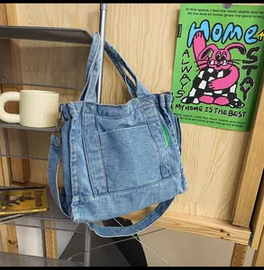 Detail of washed blue denim tote bag with green side label hanging on metal rack