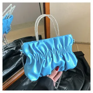 Close-up of bright blue pleated cloud bag with double rhinestone handles and silver chain