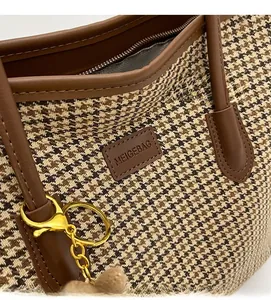 Detail of houndstooth tote bag showing leather handle and gold metal hardware