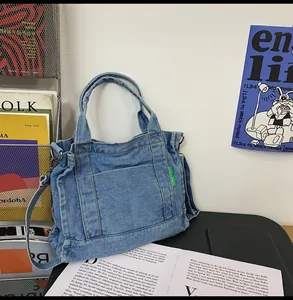 Detail of blue denim tote bag with front pocket and green tag in a lifestyle setting
