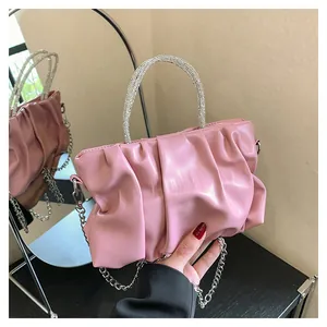Detailed view of pink pleated handbag with silver rhinestone handle and chain strap