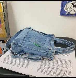 Detail of blue denim tote bag with adjustable strap and small side pocket label