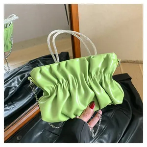 Close-up of green ruched cloud bag featuring rhinestone handles and silver chain strap