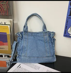 Detail of vintage washed denim tote bag with decorative stitching and silver hardware