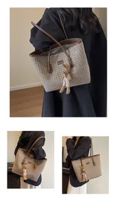 Detail of checkered tote bag featuring a plush rabbit pendant and leather trim details