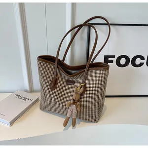 Detail of large houndstooth tote bag with brown leather trim and cute rabbit charm
