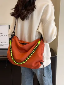 Fashionable orange tote bag with tricolor woven strap shown on a model in a modern room
