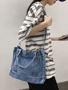Minimalist blue washed denim tote bag with adjustable shoulder strap and green brand label