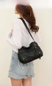 Detail of black washed leather shoulder bag with multiple zipper layers and woven texture