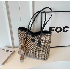 Close-up of houndstooth tote bag with leather handle and cute plush rabbit charm