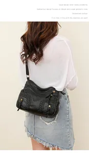Macro view of black washed leather crossbody bag showing multiple zippers and braided details