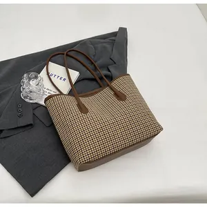 Close-up of classic brown houndstooth pattern fabric on a large tote bag with leather trim