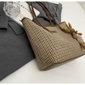 Detail of houndstooth tote bag with brown leather trim and cute rabbit plush charm