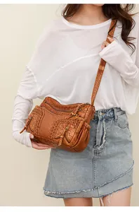 Close-up of caramel vintage washed leather crossbody bag with fringe and woven details