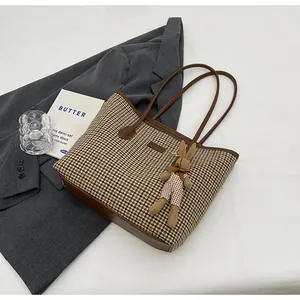 Detailed view of checkered tote bag with brown leather base and plush rabbit charm accessory