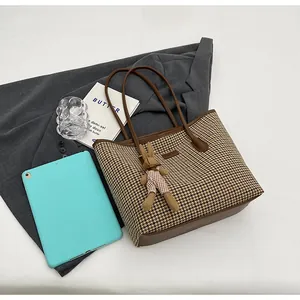 Close-up of houndstooth tote bag with brown leather straps and cute plush rabbit charm