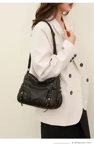 Detail of black soft washed leather shoulder bag with woven texture and tassels