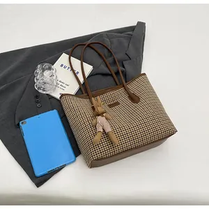 Close-up of houndstooth tote bag with brown leather handles and a cute bunny charm