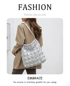 Detail van zilveren gewatteerde tote bag met bubbeltextuur op model in bruin pak
