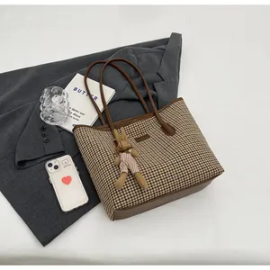 Flat lay of retro check tote bag with plush rabbit charm and dark brown leather straps
