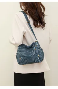 Detail of blue washed leather crossbody bag showing woven edges and tassel zipper