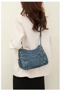 Side view of gray-blue washed leather shoulder bag with multiple zippered pockets