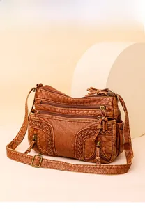 Detail view of washed leather crossbody bag with multiple zip pockets and woven texture