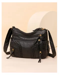 Detail view of black washed PU leather shoulder bag with multiple zippers and tassels