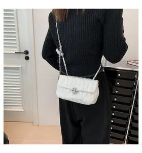 Détail du sac matelassé blanc porté en bandoulière montrant la coupe et la texture