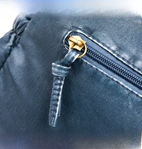 Macro shot of blue washed leather texture and golden metal zipper details on the shoulder bag