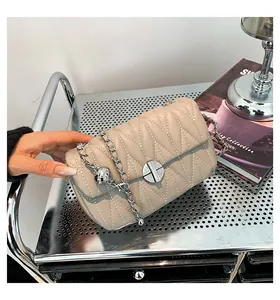 Détail du sac matelassé abricot avec coutures en V et pendentif boule argentée