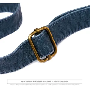 Adjustable shoulder strap detail with bronze hardware on a textured leather shoulder bag