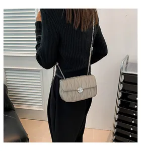 Détail du sac matelassé gris avec coutures en V et fermoir métallique argenté