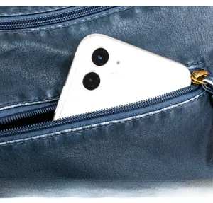 Macro detail of dark blue pebbled leather shoulder bag with functional back zipper pocket