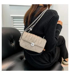Détail du sac bandoulière matelassé beige clair avec coutures en V et chaîne argentée