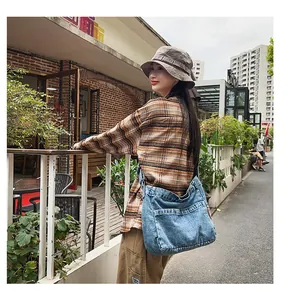 Detailed street shot of a large blue washed denim crossbody bag for casual daily wear