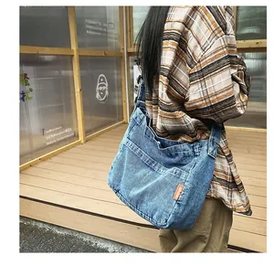 Macro detail of the dark blue denim crossbody bag with orange woven label and stitching