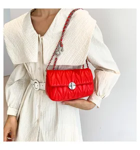 Détail du sac à bandoulière matelassé rouge avec fermoir argenté sur robe vintage
